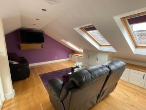 a living room with a leather couch and a tv at Apartment at Island Cottage, Inishnee, Roundstone in Galway
