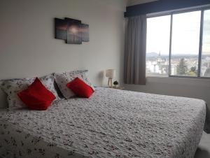 um quarto com uma cama com almofadas vermelhas e uma janela em Mountain Center em San Carlos de Bariloche