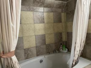 een bad met een douchegordijn in de badkamer bij Super Luxury & Cozy Lower Level Apartment in NW Calgary, AB Close to Banff in Calgary