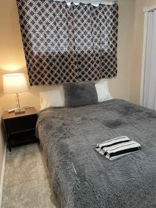 een slaapkamer met een bed met een zwart-witte deken bij Super Luxury & Cozy Lower Level Apartment in NW Calgary, AB Close to Banff in Calgary