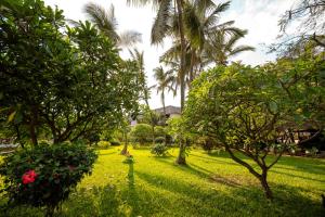 een weelderige groene tuin met palmbomen en rode bloemen bij Nungwi Beach Resort by Turaco in Nungwi
