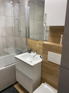 ein Badezimmer mit einem weißen Waschbecken und einer Dusche in der Unterkunft Apartament Daszyńskiego in Suwałki