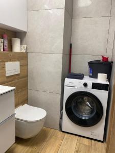ein Badezimmer mit einer Waschmaschine und einem WC in der Unterkunft Apartament Daszyńskiego in Suwałki