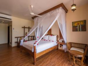 1 dormitorio con 1 cama con dosel en Nungwi Beach Resort by Turaco, en Nungwi