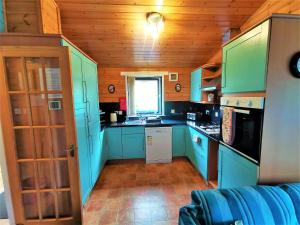 een kleine keuken met blauwe kasten en een raam bij Glen Roe - 3 Bed Lodge on Friendly Farm Stay with Private Hot Tub in New Cumnock