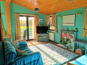 een blauwe woonkamer met een bank en een tv bij Glen Roe - 3 Bed Lodge on Friendly Farm Stay with Private Hot Tub in New Cumnock