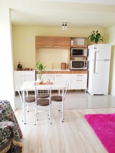 a kitchen with a table and chairs and a white refrigerator at Pôr do Sol 8 andar in Canoas