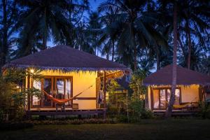 a house with a hammock and two trees at night at Baan Manali Resort in Thongsala