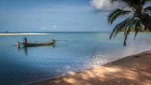 a man in a boat on the water next to a beach at Baan Manali Resort in Thongsala