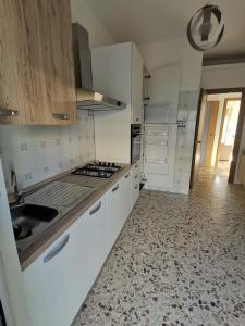 a white kitchen with a sink and a stove at Appartement Spadafora - 50m de la plage in Spadafora