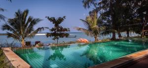 a swimming pool with a view of the ocean at Baan Manali Resort in Thongsala
