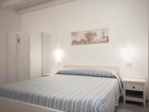 カステルヌオーヴォ・マグラにあるB&B il Lupo e la Querciaの白いベッドルーム(ストライプ毛布付きのベッド付)