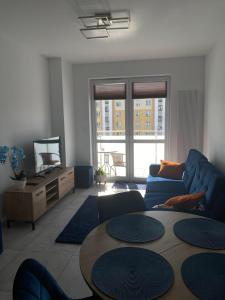 a living room with a blue couch and a table at Apartament Daszyńskiego in Suwałki