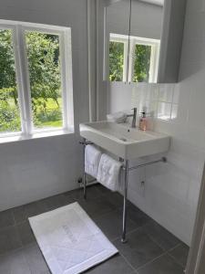 a white bathroom with a sink and a mirror at Slottsnära miljö. in Laholm