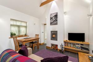 ein Wohnzimmer mit einer Couch und einem Tisch und einem Fernseher in der Unterkunft The Woodland Retreat Pembrokeshire Dog-friendly in Haverfordwest