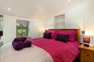ein Schlafzimmer mit einem großen rosa Bett mit lila Kissen in der Unterkunft The Woodland Retreat Pembrokeshire Dog-friendly in Haverfordwest