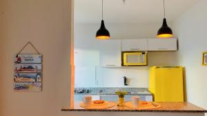 uma cozinha com 2 pratos e um frigorífico amarelo em Studios Unamar em Cabo Frio