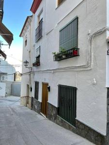 a white building with a door and windows on a street at Casa ' A ca Paca ' in Lanjarón