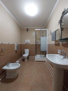 a bathroom with two sinks and a shower and a toilet at Apart-hotel 24/7 in Kamianets-Podilskyi
