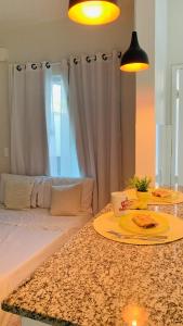 a room with a bed and a table with a plate on it at Studios Unamar in Cabo Frio