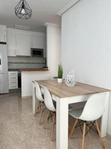 uma cozinha com uma mesa de madeira e cadeiras brancas em Ático duplex con Vista Mar y Terraza Privada a 200m de la playa hasta 6 personas em Garrucha