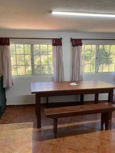 una mesa y un banco en una habitación con ventanas en Vivenda Ribeiro - Curral das Freiras en Curral das Freiras