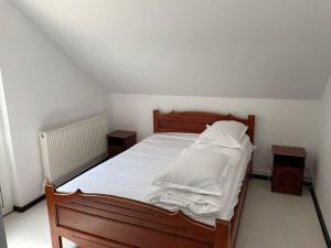 Schlafzimmer mit einem Holzbett mit weißer Bettwäsche in der Unterkunft Pensiunea Pe drumuri de munte in Borca