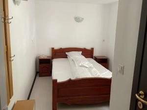 a small bedroom with a wooden bed with white sheets at Pensiunea Pe drumuri de munte in Borca