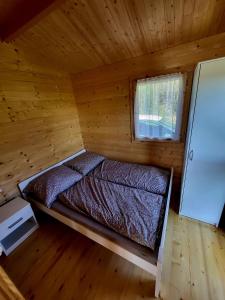 łóżko w drewnianym domku z oknem w obiekcie Domki na Górce w mieście Wądzyn