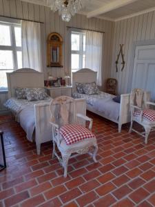 a bedroom with two beds and two chairs and a chandelier at Ängbacka in Rejmyre