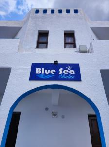 un bâtiment blanc avec un panneau bleu dans l'établissement Blue Sea Studios, à Arkasa