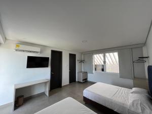 a bedroom with a bed and a desk and a tv at Hotel Emerawaa Centro Historico in Ríohacha