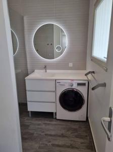 a bathroom with a washing machine and a sink at Superbe studio lumineux, vue sur piscine et mer in Baie Nettle