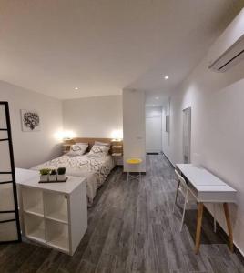 ein weißes Schlafzimmer mit einem Bett und einem Schreibtisch in der Unterkunft Superbe studio lumineux, vue sur piscine et mer in Baie Nettle