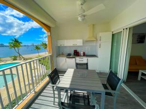 balcón con mesa y vistas al océano en Superbe studio lumineux, vue sur piscine et mer en Baie Nettle