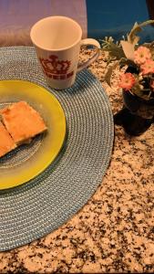 a table with a plate with a piece of cake and a cup at Studios Unamar in Cabo Frio