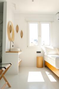 a white bedroom with a bed and two windows at Eleana Hotel in Tinos Town