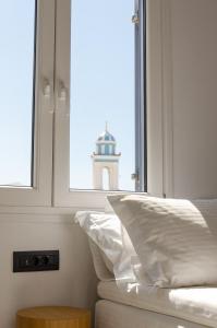 a bedroom with a window with a lighthouse in the background at Eleana Hotel in Tinos Town