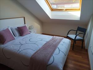 a bedroom with a bed and a window and a chair at HyP - Ático Forneira in Arcade