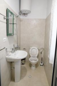 a white bathroom with a toilet and a sink at Logli Apartments in Gjirokastër