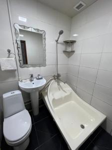 a white bathroom with a toilet and a sink at Iso Hostel in Tashkent