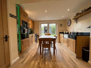 a kitchen with wooden floors and a table with chairs at Holly Farm Cottage in Flixton