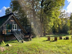 a log cabin in a field of grass with trees at Stimbekhof in Bispingen