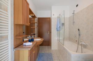 bagno con vasca, lavandino e doccia di ZARA HOUSE - Lake and Pet Friendly a Brusimpiano