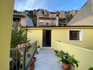 a yellow house with a balcony with plants at B&b Boladina Experience in Baunei