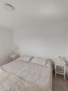 a white bedroom with a bed and two tables at Departamento PARQUE in Paraná