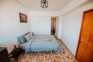 sypialnia z łóżkiem z niebieską pościelą i oknem w obiekcie La Perla Del Puerto w mieście Gandía