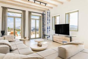 un soggiorno con un grande divano e una TV a schermo piatto di Panormos Bay Suites Luxury Resort a Mykonos Città