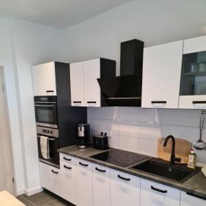 a kitchen with white cabinets and black appliances at Suite Crissie in Bernburg