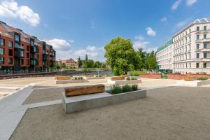 a park with a bench in a city with buildings at Apartament Mały PRL - Młyn Maria - Art Apartments in Wrocław